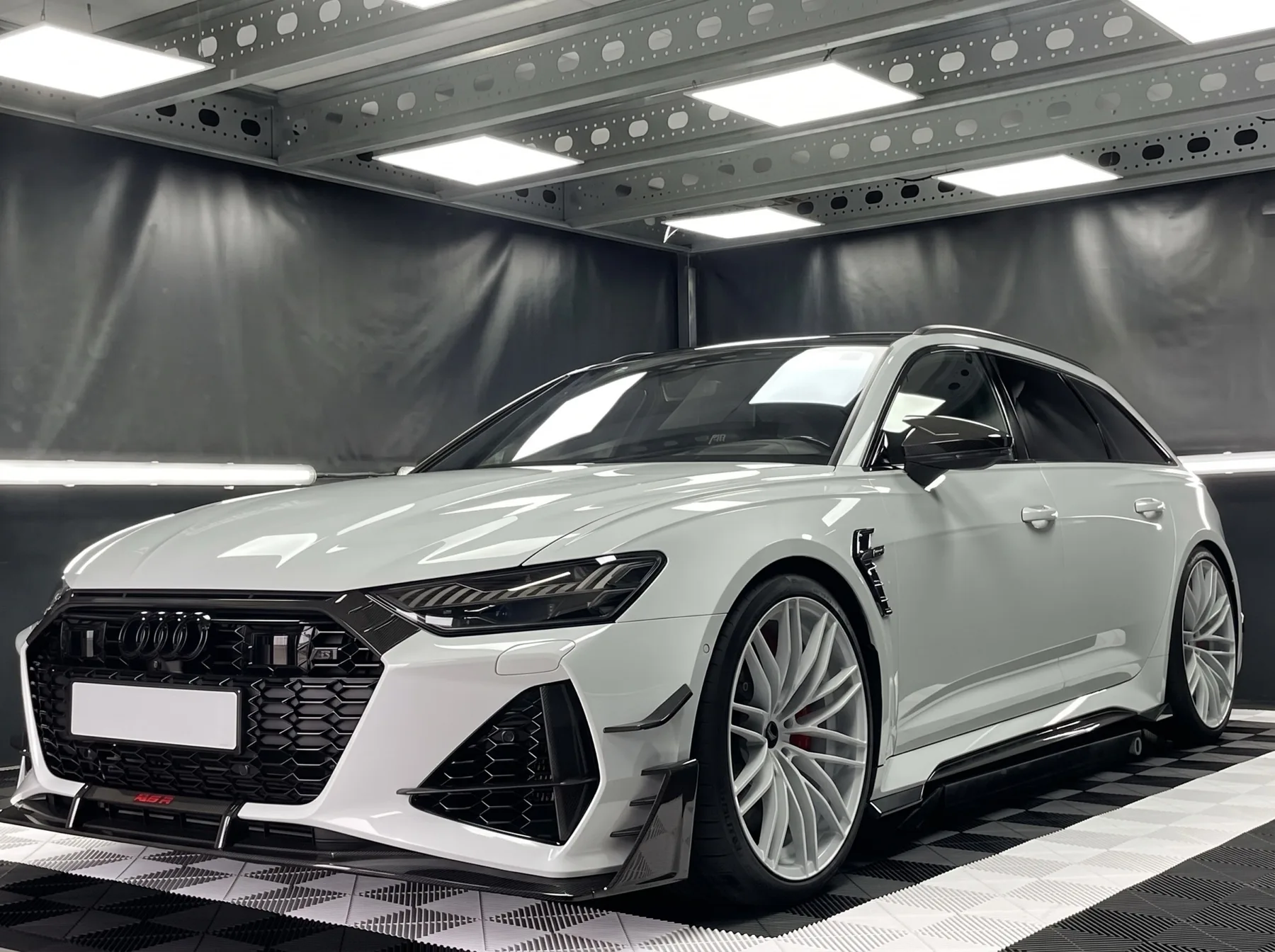 Lichtgrijze Audi RS6 in een detailingstudio, waarin de lichtbalken als scherpe rechte lijnen in de lak weerspiegelen