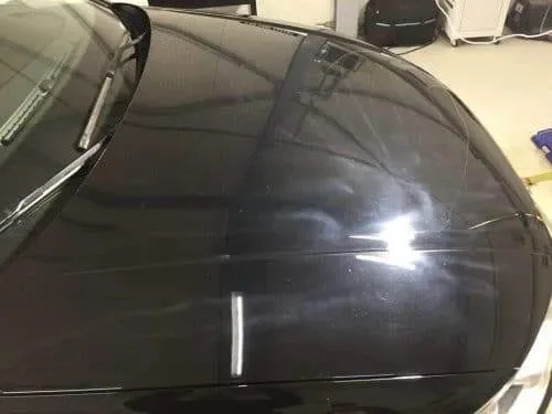 Zwarte motorkap met brede lichte vegen die alleen onder fel licht zichtbaar zijn