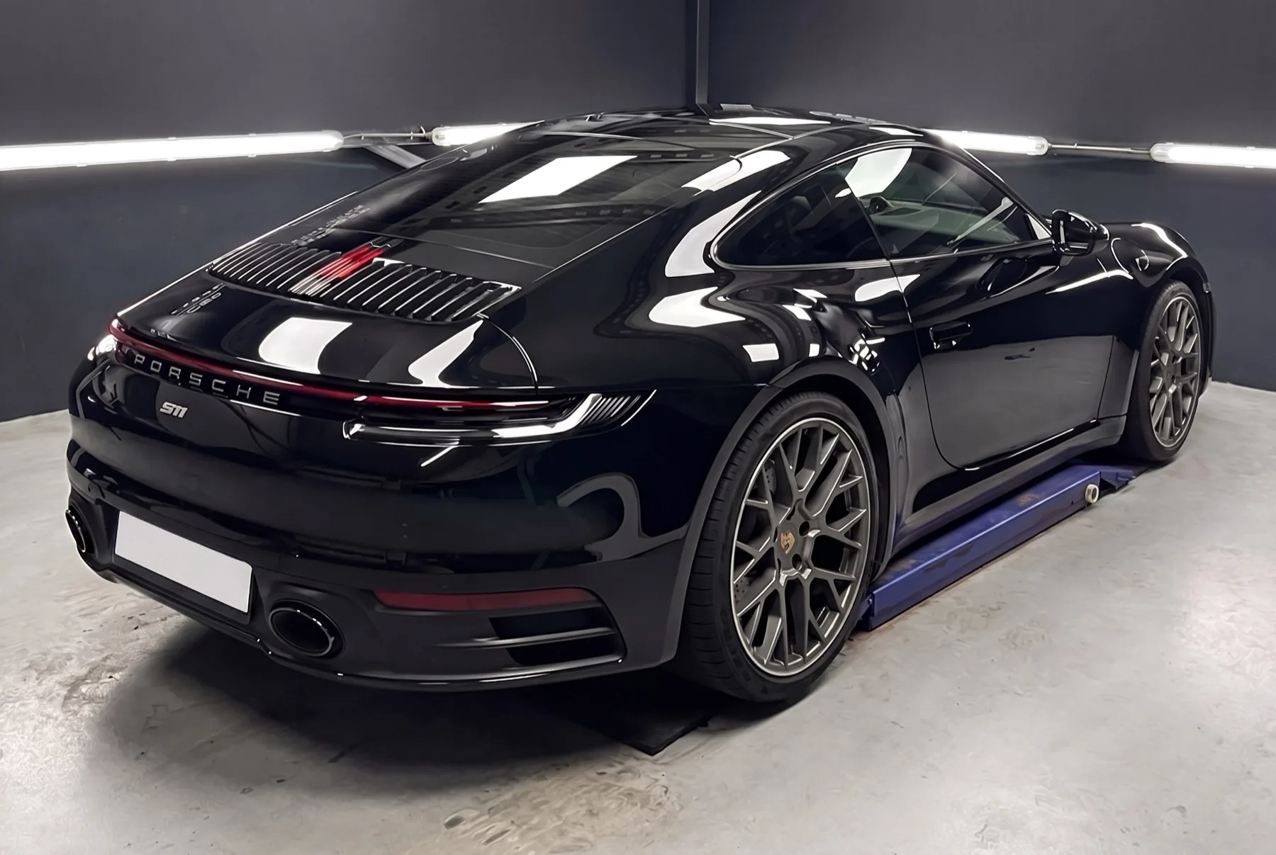 Zwarte Porsche 911 met lakbeschermingsfolie in een detailingstudio onder ledverlichting