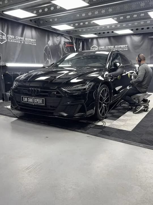 Polijstmachine op de zwarte lak van een Audi S7, met werklicht erlangs