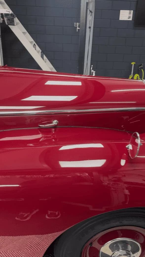 Detail van donkerrode Bentley-lak na lakcorrectie, met een strakke reflectie