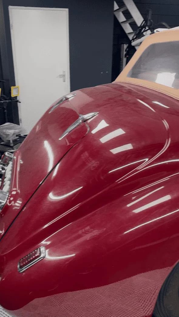 Donkerrood voorscherm van een Bentley oldtimer met een cabriokap, in de studio