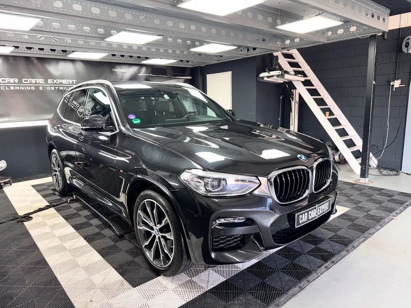Zwarte BMW X3 in driekwart aanzicht tijdens de behandeling in de studio