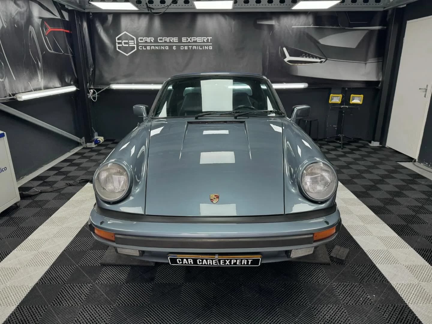 Grijsblauwe Porsche 911 SC recht van voren in de detailingstudio