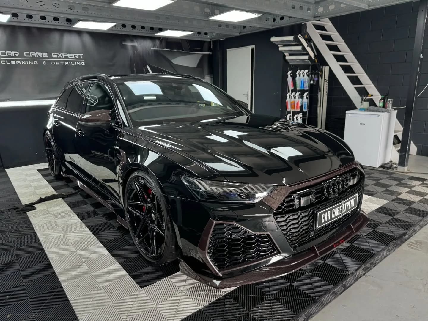 Zwarte Audi RS6 ABT in driekwart vooraanzicht met scherpe reflecties in de flank