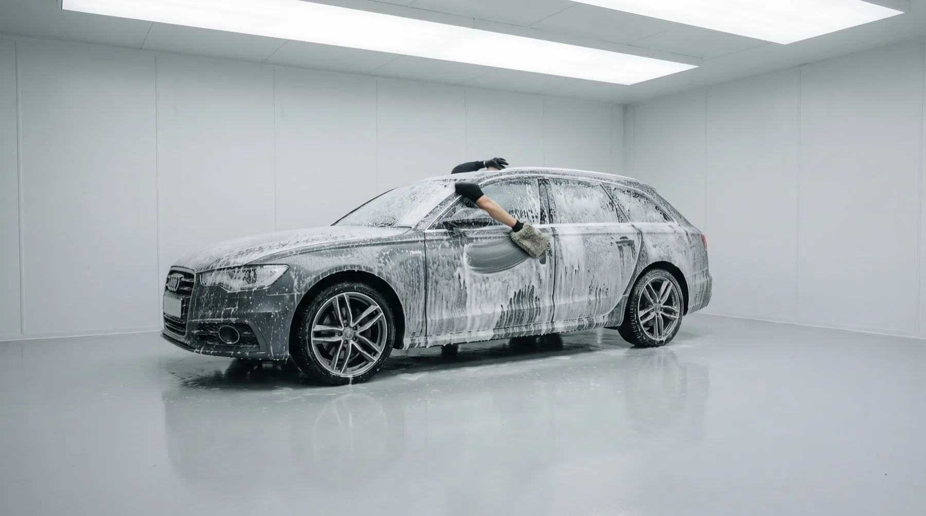 Auto onder een dikke laag snowfoam in een smetteloze detailingstudio