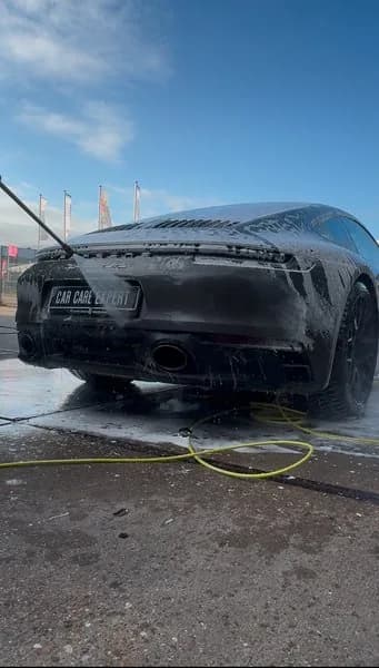 Afspuiten van het schuim op een donkergrijze Porsche 911
