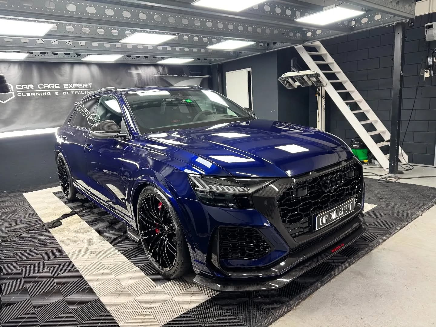 Donkerblauwe Audi RSQ8-S ABT in driekwart vooraanzicht na de behandeling, met scherpe reflecties in de flank