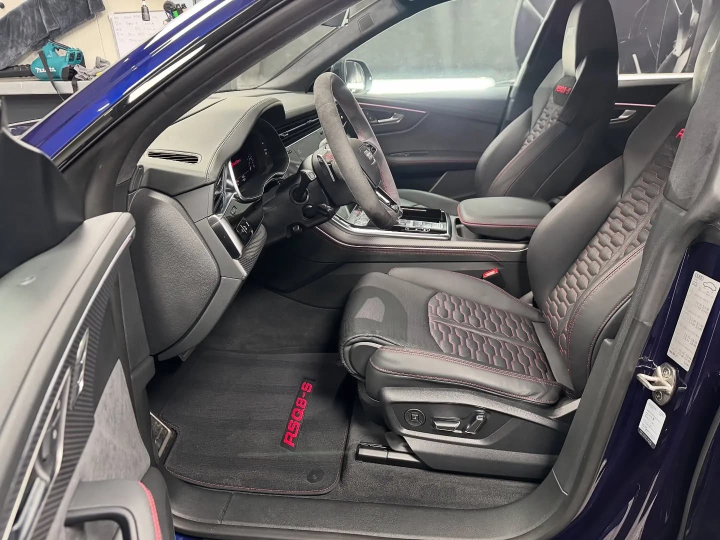 Zwart lederen interieur van een Audi RSQ8-S met rode stiksels, alcantara stuur en RSQ8-S matten