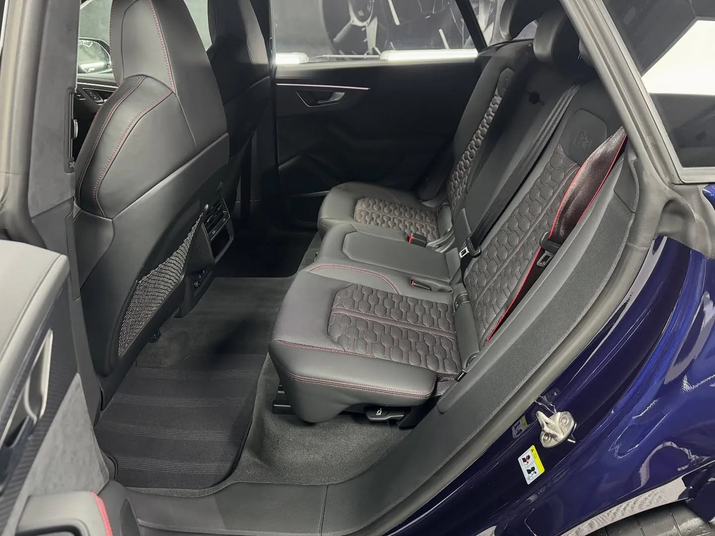 Achterbank van een Audi RSQ8-S met geperforeerd leer en rode stiksels, na reiniging