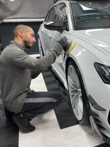Samir Elouariachi polijst met de machine een voorscherm van een witte Audi in zijn werkplaats